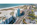 Expansive aerial view showcasing the condo building, the adjacent beach, and the lively street below at 11000 Gulf Blvd # 1004, Treasure Island, FL 33706