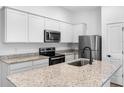 Bright kitchen features stainless steel appliances, granite countertops, and white cabinets at 11047 Flycatcher Rd, Brooksville, FL 34614