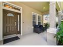 Inviting front porch with stylish seating, neutral wall color, and a view of the neighborhood at 13310 Tiger Lilly Ln, Tampa, FL 33625