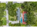 Aerial view showcases a private estate with pool, tennis court, lush landscaping and mature trees at 1628 Long Bow Ln, Clearwater, FL 33764