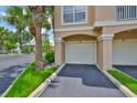 Attached garage with a paved driveway, lush green grass, and landscaping on both sides at 2201 Bay Club Cir, Tampa, FL 33607