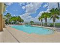 Community pool with a waterfall feature, sun loungers, palm trees, and serene water views at 2201 Bay Club Cir, Tampa, FL 33607