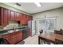 Functional kitchen featuring dark wood cabinetry, modern stainless steel appliances, and eat-in table near sliding doors at 243 Alexander Woods Dr, Plant City, FL 33563