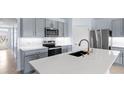 Modern kitchen features stainless steel appliances, stylish gray cabinets, and a spacious quartz island at 33369 Hamilton Hill Ln, Wesley Chapel, FL 33545
