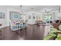 Bright and airy living room featuring dark wood floors, elegant furnishings, and sliding glass doors to the lanai at 34811 Arbor Green Pl, Zephyrhills, FL 33541