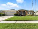 Beautiful single-story home with arched windows, a well-manicured lawn, and a spacious driveway at 4428 Gevalia Dr, Brooksville, FL 34604
