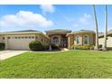 Beautiful single-story home with arched windows, a well-manicured lawn, and a spacious driveway at 4428 Gevalia Dr, Brooksville, FL 34604