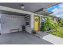 Covered carport leading to a yellow front door with a wreath, accented by greenery and stylish details at 5741 91St N Ave, Pinellas Park, FL 33782