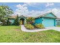 Charming blue home with a well-kept lawn, palm trees, and a welcoming yellow double-door entrance at 7046 Frascati Loop, Wesley Chapel, FL 33544
