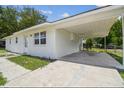 View of the home's exterior showing the white textured siding, carport, and driveway at 9259 Marler Rd, Spring Hill, FL 34608