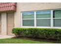 Close exterior of the condo building showing unit 4, a window, and manicured shrubbery at 10033 64Th N Ave # 4, St Petersburg, FL 33708