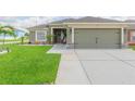Lovely single-Gathering home featuring an attached two-car garage, a tidy lawn, and a welcoming entryway at 11913 Butler Woods Cir, Riverview, FL 33579