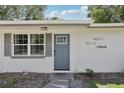 Close up of a charming home featuring a blue front door and well-manicured landscaping at 1438 Poinciana Dr, Clearwater, FL 33764