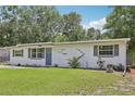 Charming single-story home featuring a well-maintained lawn and a blue front door at 1438 Poinciana Dr, Clearwater, FL 33764