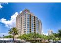 Beautiful high-rise condominium building featuring a light tan exterior, curved balconies, and verdant, mature landscaping at 288 Beach Ne Dr # 12C, St Petersburg, FL 33701
