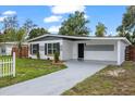 Inviting home exterior featuring a concrete driveway, landscaped lawn, and a charming white and gray facade at 4020 N Falkenburg Rd, Tampa, FL 33610