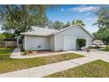 Charming single-story home with light gray siding and a single-car garage and mature trees at 4532 Cedarwood Village Dr, Tampa, FL 33624