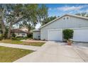 Charming single-story home with light gray siding, complemented by a well-maintained lawn and mature trees at 4532 Cedarwood Village Dr, Tampa, FL 33624