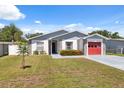 Charming single-story home featuring a red garage door, stone accents, and well-maintained landscaping at 6209 S Harold Ave, Tampa, FL 33616
