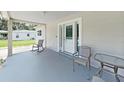 Inviting front porch featuring neutral paint, chairs, table, and a clear view of the front yard at 9413 Forest Hills Dr, Tampa, FL 33612