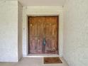 A close-up view of a beautiful wooden double door entryway with textured walls and a welcome mat at 950 Waverly St, Oldsmar, FL 34677