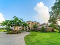 Beautiful two-story home featuring a circular driveway, lush lawn, and mature trees at 12125 Stonelake Ranch Blvd, Thonotosassa, FL 33592