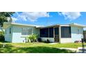 Rear exterior view highlighting a screened in porch, windows with blinds, and a well maintained lawn at 1407 Coral Ridge Dr, Punta Gorda, FL 33950