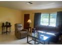 Cozy living room featuring comfortable seating, warm lighting, and a large window overlooking the yard at 1480 Fairfield Dr, Clearwater, FL 33764