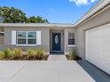 Inviting front entrance with a blue door, light-colored brick accents, and lush landscaping at 1675 E Grovehill Rd, Palm Harbor, FL 34683