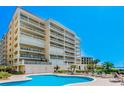 Enjoy the refreshing community pool with ample lounge space, palm trees, and stunning views of the beachfront condo building at 17720 Gulf Blvd # A702, Redington Shores, FL 33708