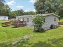 Backyard view of single-story home with deck, ramp, green lawn, and landscaping at 26223 Chianina Dr, Wesley Chapel, FL 33544
