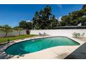 Relaxing backyard pool with lounge chairs and green table set behind a white privacy fence at 3700 56Th N St, St Petersburg, FL 33710