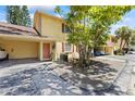 Townhouse exterior featuring covered parking, a vibrant tree, and well-maintained landscaping at 7608 Pasa Dobles Ct, Tampa, FL 33615