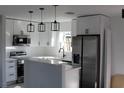 Modern kitchen with stainless steel appliances, white cabinets, and stylish pendant lighting at 8524 Fish Lake Rd, Tampa, FL 33619