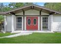 Close-up of a home's entrance featuring an eye-catching red double door and manicured lawn at 8610 Fish Lake Rd, Tampa, FL 33619