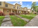 Exterior view of townhomes featuring a well-manicured lawn, walkways, and inviting facades at 10947 Brickside Ct, Riverview, FL 33579