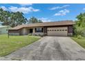 Single-story home featuring a well-maintained lawn and a concrete driveway leading to a garage at 1309 Sandalwood Dr, Plant City, FL 33563