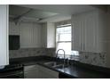 Bright kitchen with a stainless steel sink, white cabinetry, and dark countertops at 13627 San Rafael Dr, Largo, FL 33774