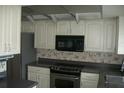 This kitchen features white cabinetry, stainless steel appliances and dark countertops at 13627 San Rafael Dr, Largo, FL 33774