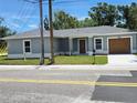 Street view of a renovated single-story home with manicured lawn, light gray stucco, and a one-car garage at 1557 S Martin Luther King Jr Ave, Clearwater, FL 33756