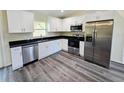 Bright kitchen featuring modern stainless steel appliances, white cabinets, and dark countertops at 1557 S Martin Luther King Jr Ave, Clearwater, FL 33756