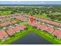 Aerial view of a neighborhood with manicured lawns, red-tiled roofs, and a serene pond at 17415 Holly Well Ave, Wimauma, FL 33598