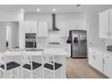 Modern kitchen showcasing stainless steel appliances, white cabinetry, an island, and stylish barstools at 17415 Holly Well Ave, Wimauma, FL 33598