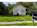 A cute yellow single story house with a traditional design, small front yard, and an overgrown lawn at 514 Woodlawn St, Clearwater, FL 33756