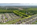 Aerial view of land for sale between neighborhood and wooded area with a yellow rectangular border at 11109 Sumner Rd, Wimauma, FL 33598