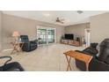 Spacious living room with tile flooring, comfortable seating, ceiling fan, and a sliding glass door leading to the outdoors at 15612 Farnsworth Ln, Tampa, FL 33624