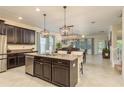 Spacious kitchen with dark cabinetry, granite countertops, and a large island with pendant lighting at 19309 Prairie Tree Pl, Tampa, FL 33647