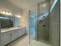 Modern bath with double vanity, sleek fixtures, and glass shower with tiled walls and rainfall shower head at 4947 Ribbon Rock Cv, Lakewood Ranch, FL 34211