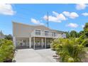 Stunning elevated home with concrete driveway, beautiful landscaping, and white support beams at 6924 Americana Ne Dr # 167, St Petersburg, FL 33702