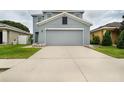 Home with a two-car garage and driveway surrounded by green grass and rock gardens at 11926 Grand Kempston Dr, Gibsonton, FL 33534
